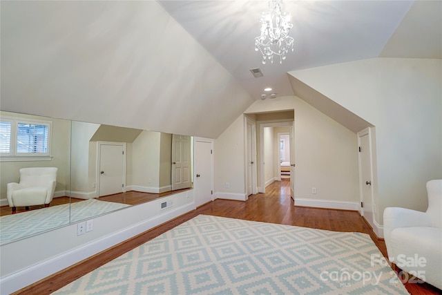 additional living space with a notable chandelier, vaulted ceiling, and light wood-type flooring