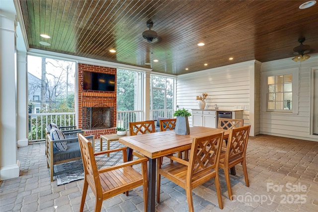 interior space featuring wood walls, wood ceiling, a wall of windows, ceiling fan, and a fireplace