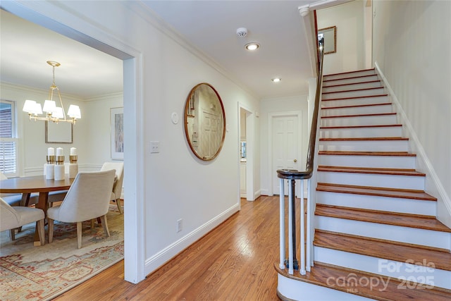 staircase featuring crown molding, a chandelier, and hardwood / wood-style floors