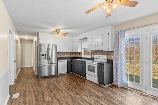 kitchen featuring white appliances, white cabinets, dark hardwood / wood-style floors, and decorative backsplash