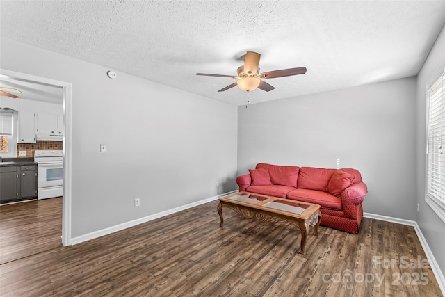 living room with ceiling fan, sink, dark hardwood / wood-style floors, and a textured ceiling