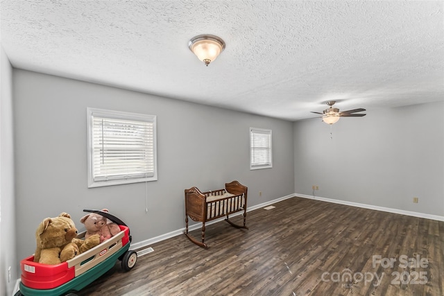 interior space featuring ceiling fan, dark wood-type flooring, and a textured ceiling