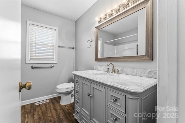 bathroom with hardwood / wood-style flooring, vanity, toilet, and a shower