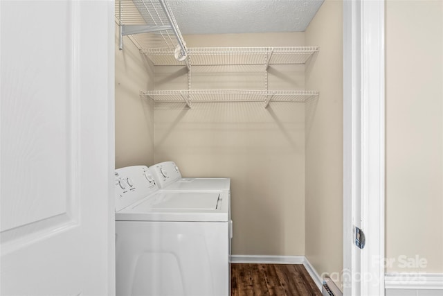 laundry room with washing machine and dryer, a textured ceiling, dark hardwood / wood-style flooring, and baseboard heating