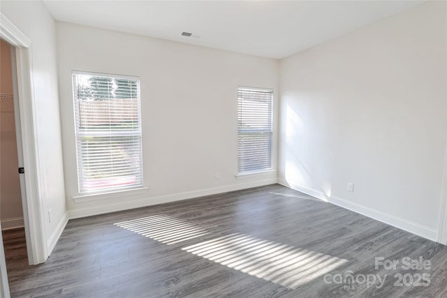 unfurnished room with plenty of natural light and dark hardwood / wood-style flooring