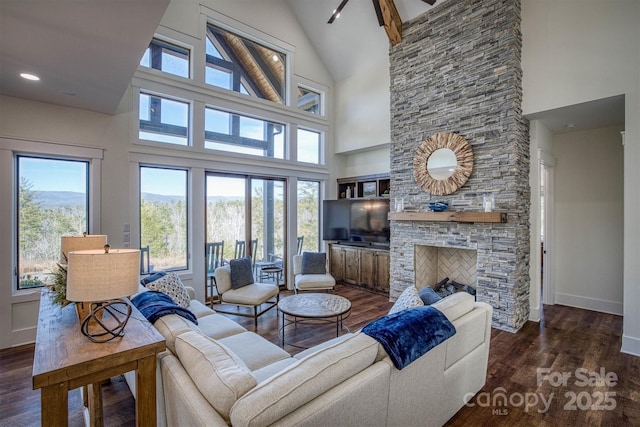 living room with plenty of natural light, dark hardwood / wood-style flooring, high vaulted ceiling, and a stone fireplace