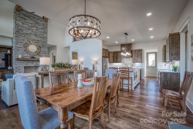 dining room with an inviting chandelier, dark hardwood / wood-style floors, sink, and a stone fireplace