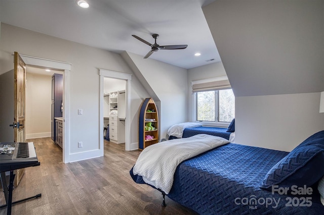 bedroom with ceiling fan, a walk in closet, and wood-type flooring