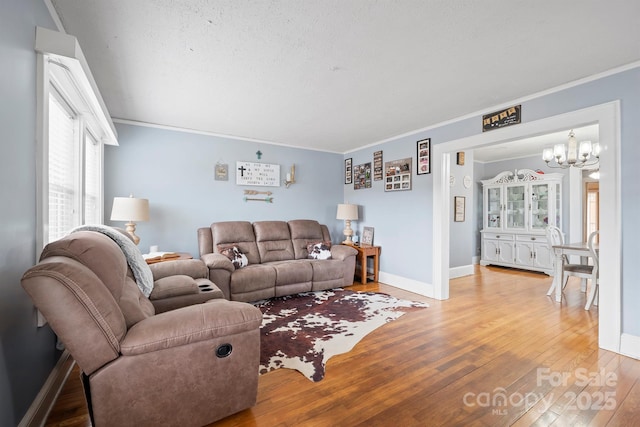 living room featuring ornamental molding, a chandelier, hardwood / wood-style floors, and a textured ceiling