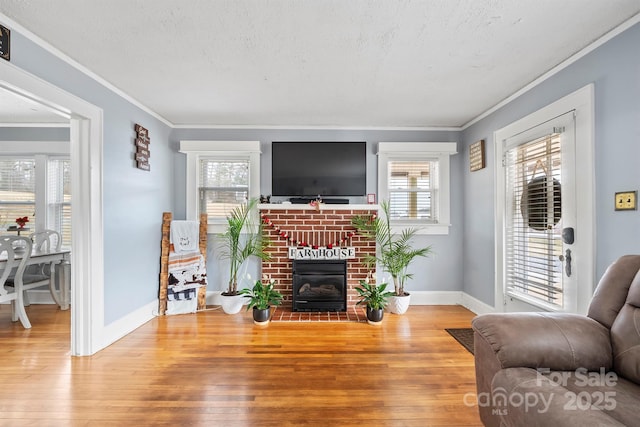 living room with a fireplace, ornamental molding, a textured ceiling, and light wood-type flooring