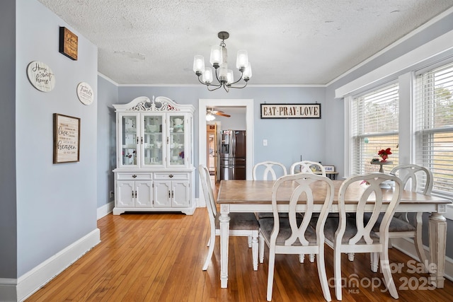 dining space with crown molding, ceiling fan with notable chandelier, a textured ceiling, and light wood-type flooring