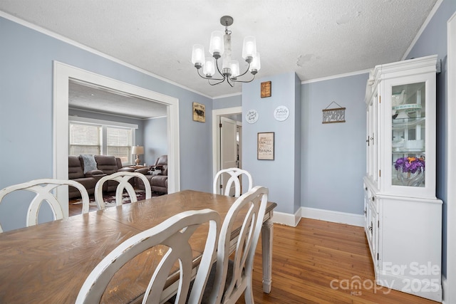 dining area with crown molding, hardwood / wood-style floors, a textured ceiling, and a chandelier