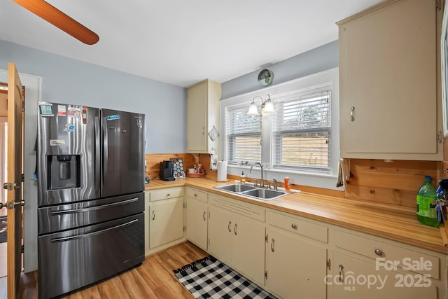 kitchen with sink, stainless steel fridge, hanging light fixtures, and cream cabinets