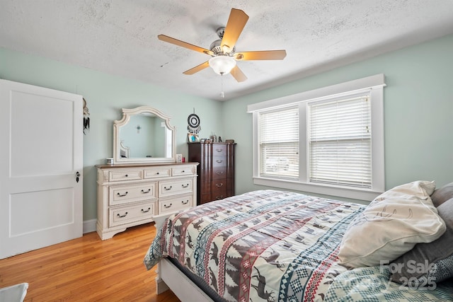 bedroom featuring ceiling fan, light hardwood / wood-style floors, and a textured ceiling