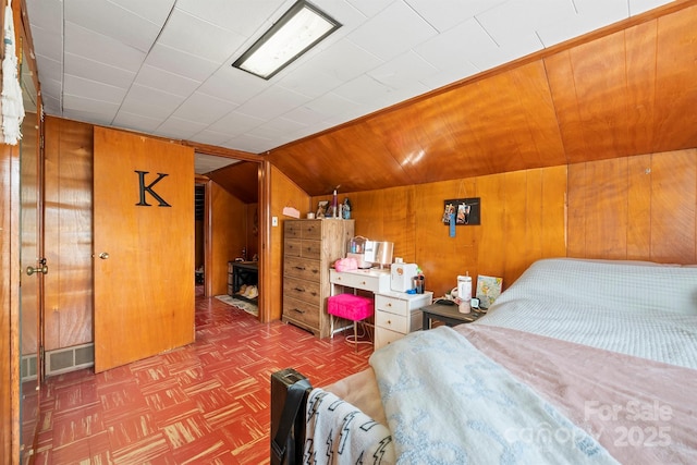 bedroom with wooden walls and vaulted ceiling