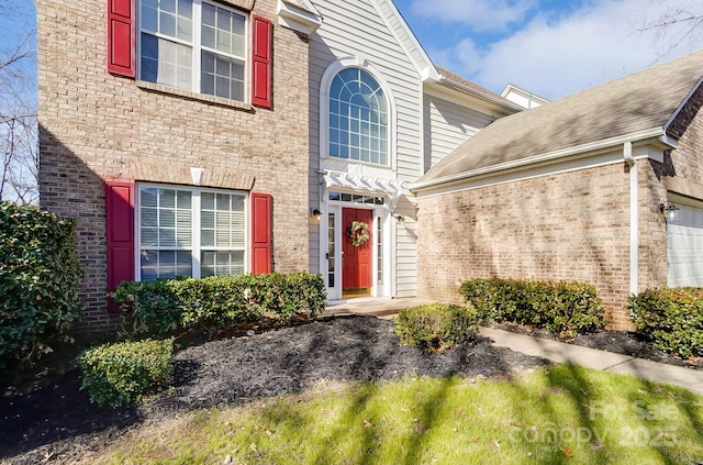 entrance to property with an attached garage and brick siding