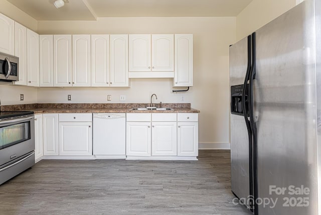 kitchen with stainless steel appliances, white cabinetry, sink, and light hardwood / wood-style flooring