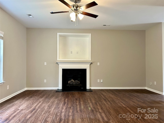 unfurnished living room with visible vents, a fireplace with raised hearth, baseboards, a ceiling fan, and dark wood-style flooring