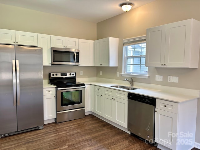 kitchen with dark wood finished floors, a sink, stainless steel appliances, light countertops, and white cabinets