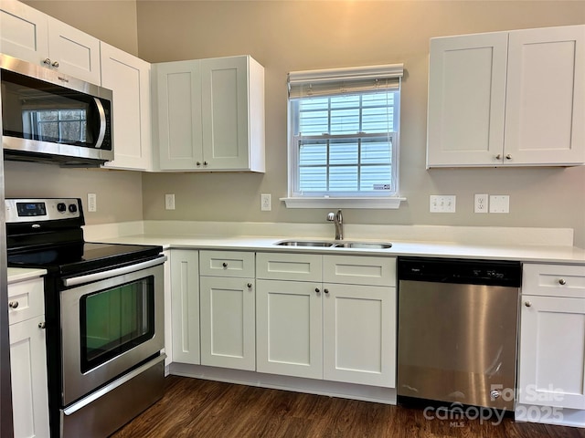 kitchen with a sink, stainless steel appliances, white cabinetry, and light countertops