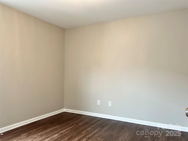 spare room with baseboards and dark wood-style flooring