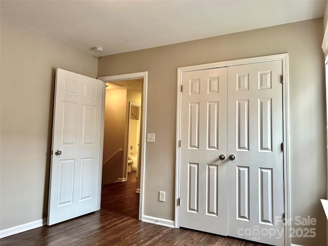 bedroom with a closet, baseboards, and dark wood-style flooring