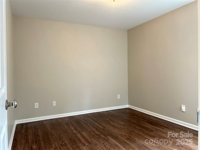 empty room featuring dark wood-type flooring and baseboards