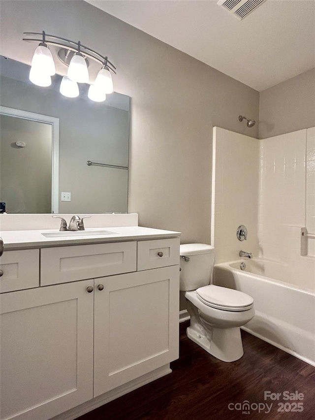 bathroom featuring visible vents, tub / shower combination, toilet, wood finished floors, and vanity