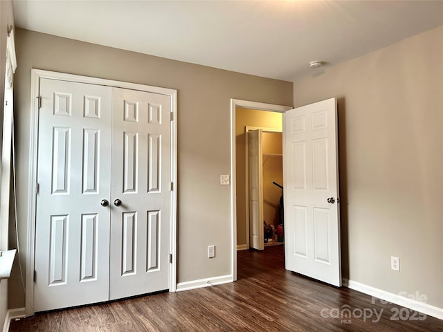 unfurnished bedroom featuring a closet, baseboards, and dark wood finished floors