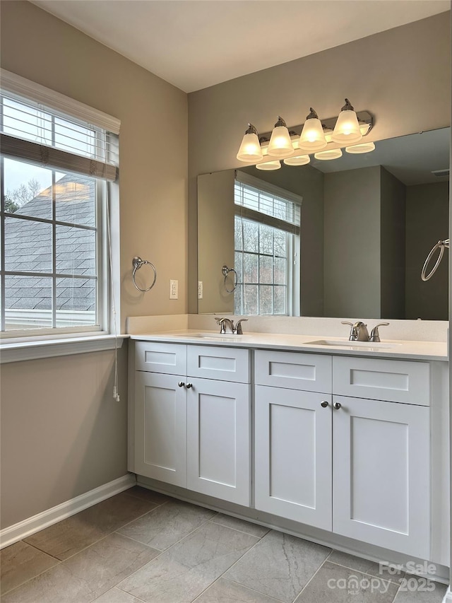 full bath featuring double vanity, baseboards, and a sink