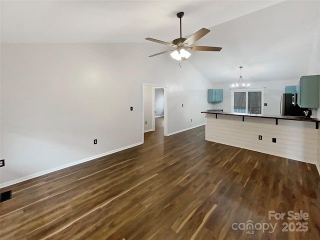 unfurnished living room featuring high vaulted ceiling, dark hardwood / wood-style flooring, and ceiling fan with notable chandelier