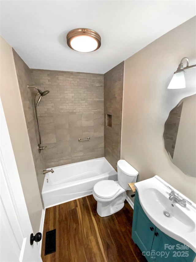 full bathroom featuring vanity, toilet, tiled shower / bath combo, and hardwood / wood-style floors