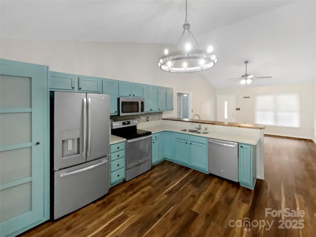 kitchen with vaulted ceiling, appliances with stainless steel finishes, pendant lighting, blue cabinets, and sink