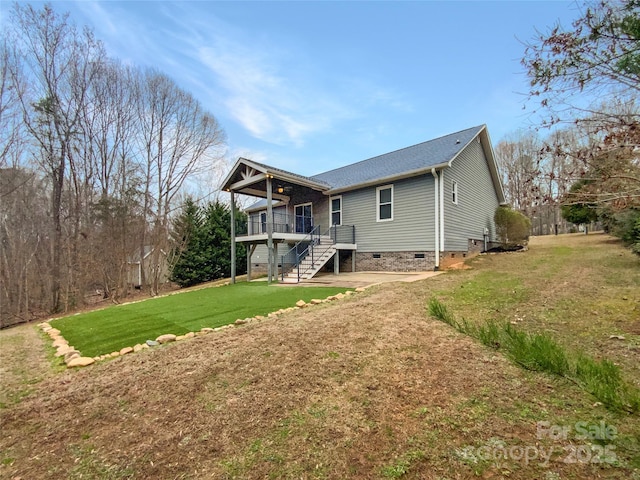 rear view of house featuring a wooden deck and a lawn