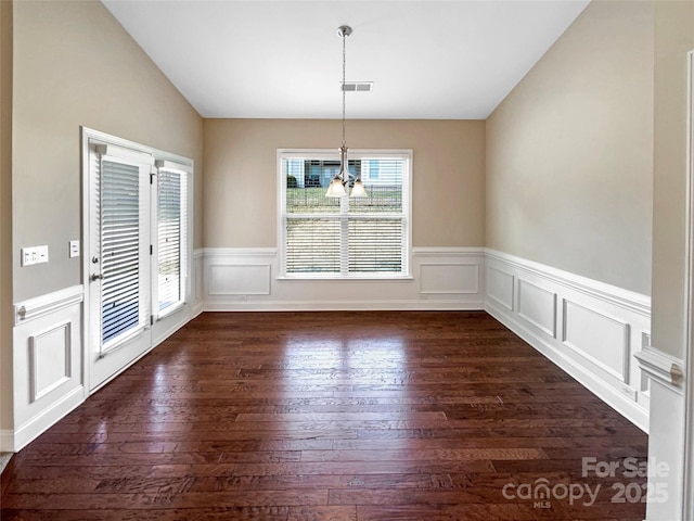 unfurnished dining area featuring vaulted ceiling and dark hardwood / wood-style flooring