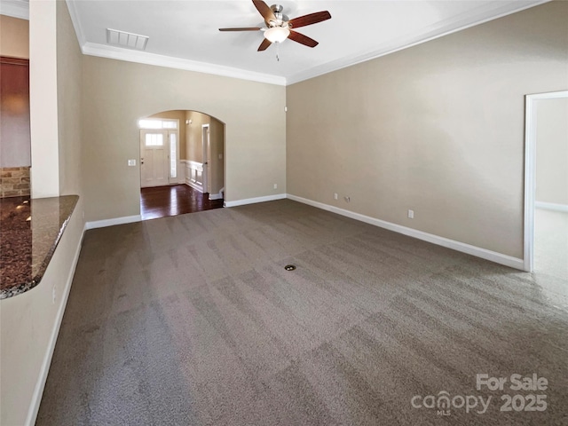 unfurnished living room with dark colored carpet, crown molding, and ceiling fan