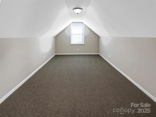 additional living space with lofted ceiling and dark colored carpet