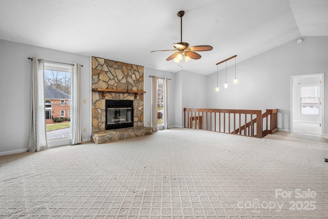 unfurnished living room featuring lofted ceiling, ceiling fan, a fireplace, a textured ceiling, and light carpet