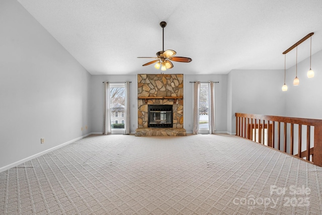 unfurnished living room with plenty of natural light, carpet floors, and a stone fireplace