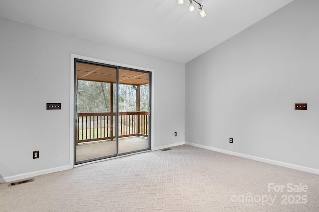 spare room with lofted ceiling, track lighting, and light colored carpet