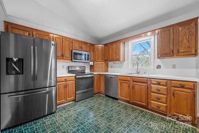 kitchen featuring appliances with stainless steel finishes, sink, and lofted ceiling