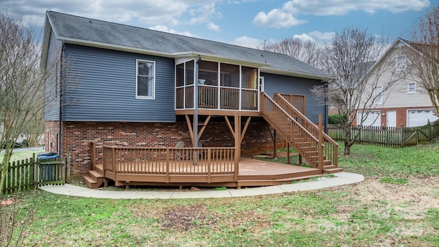 rear view of property with a lawn, a sunroom, and a deck