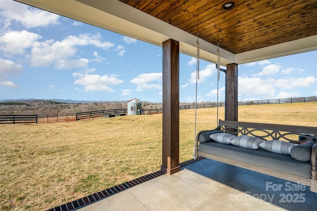 view of yard featuring a rural view, a storage shed, and a patio