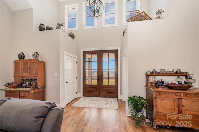 entryway with a high ceiling, light hardwood / wood-style floors, and french doors