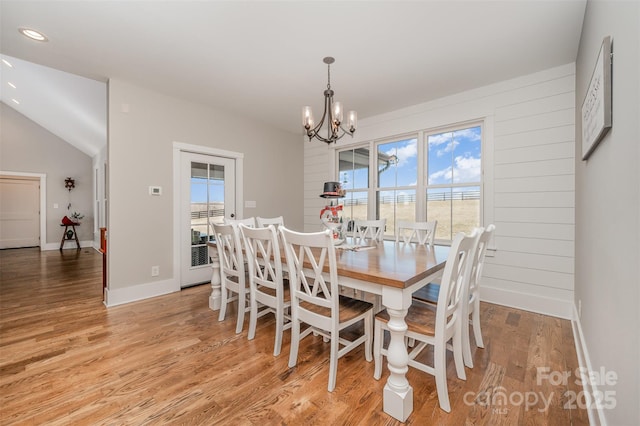 dining room with vaulted ceiling, a chandelier, and light hardwood / wood-style floors