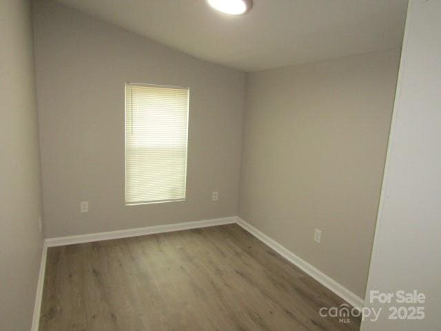 unfurnished room with lofted ceiling and hardwood / wood-style floors