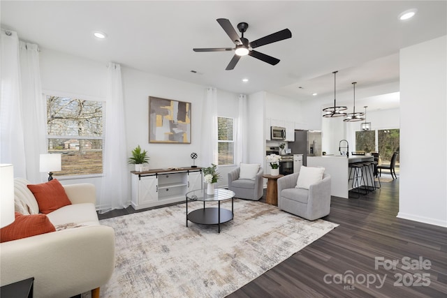 living room featuring dark wood-type flooring, sink, and ceiling fan