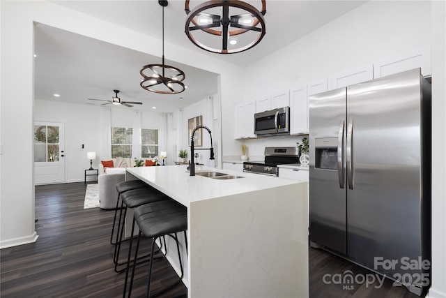 kitchen with sink, white cabinetry, a center island with sink, stainless steel appliances, and a kitchen bar