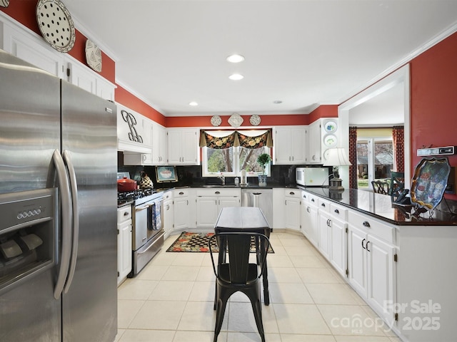 kitchen with appliances with stainless steel finishes, plenty of natural light, white cabinets, and decorative backsplash