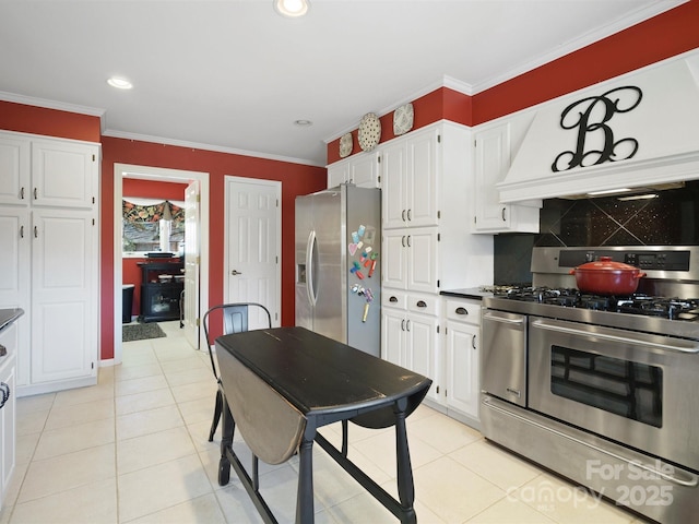 kitchen featuring light tile patterned floors, crown molding, appliances with stainless steel finishes, white cabinetry, and tasteful backsplash